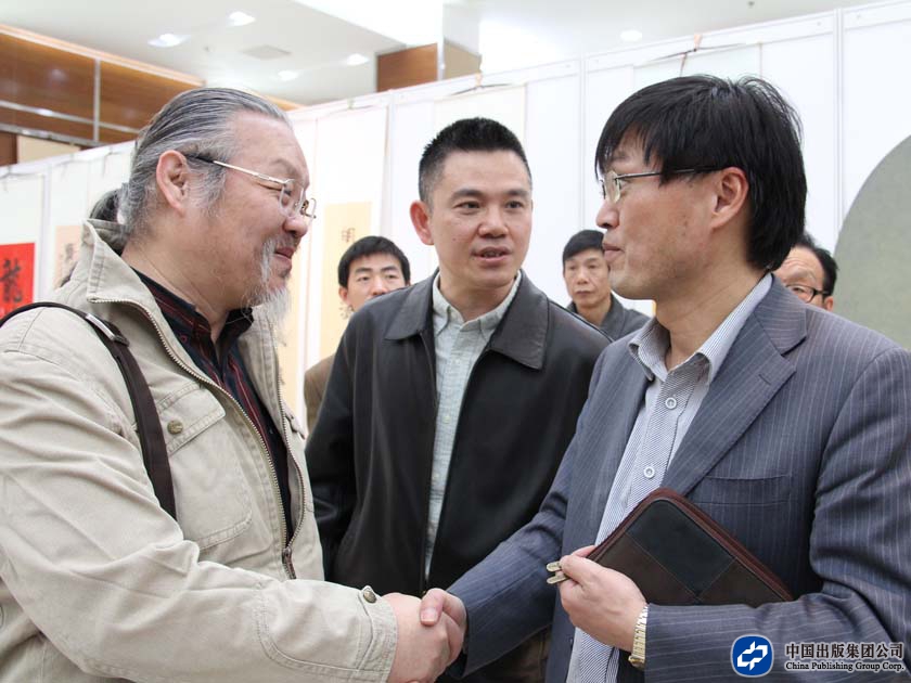 中国出版集团公司出版业务部主任张贤明与书画摄影作者握手交谈
