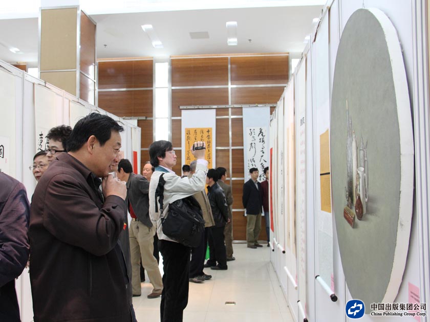中国出版集团公司副总裁王俊国在仔细观看书画摄影作品