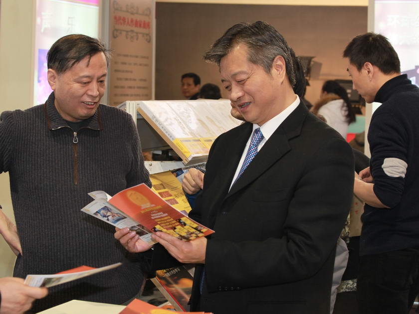 谭跃总裁视察中国出版集团公司展台，翻看人民音乐出版社出版的图书。