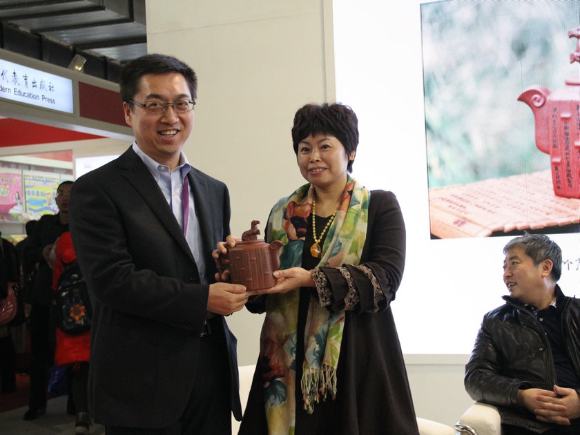 图为青年紫砂工艺美术师贺洪梅向中国出版集团公司赠送“竹简马羊壶”。