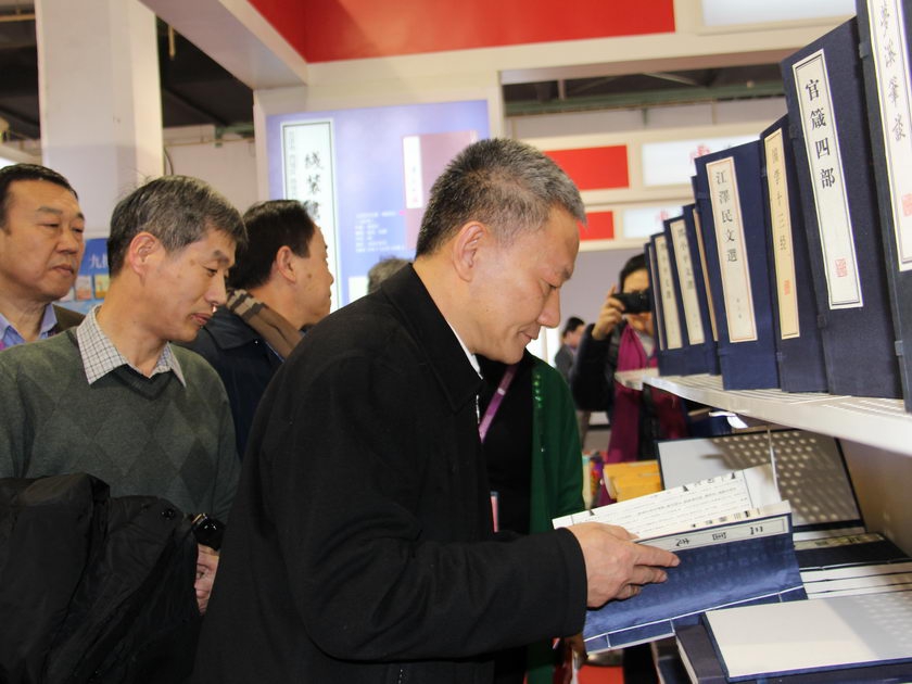 2014年1月10日，在北京图书订货会上，国家新闻出版广电总局副局长邬书林翻阅线装书局出版的线装图书。（摄影：李培芝）