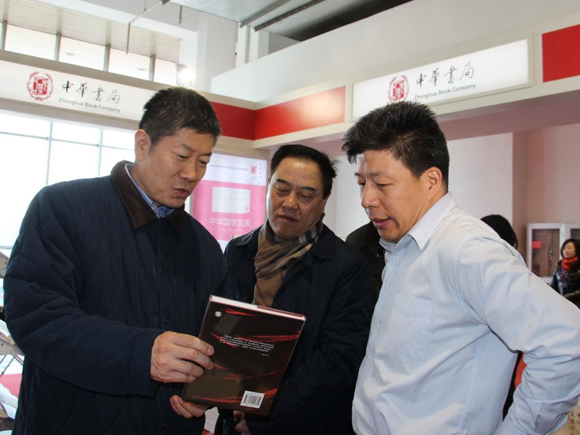 2014年1月10日，在北京图书订货会上，国家新闻出版广电总局副局长阎晓宏来到中华书局展区，图为正在听取对图书的介绍。（摄影：李培芝）