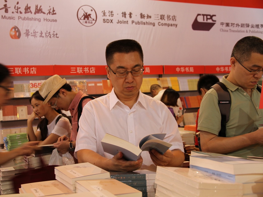 中国出版集团公司副总裁李岩翻阅集团公司展区内图书。