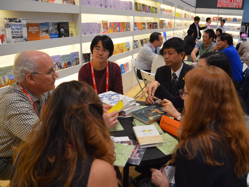中国美术出版总社总编辑林阳在中国出版集团展区与外国出版商交流洽谈。