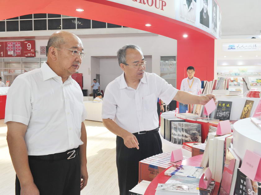8月26日，一年一度的北京国际图书博览会（BIBF）正式拉开序幕。图为中国出版集团公司党组书记王涛视察集团展区，出版部主任刘祚臣介绍情况。