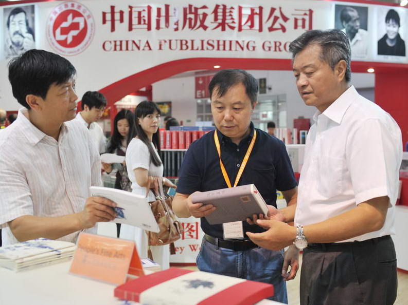 8月26日，一年一度的北京国际图书博览会（BIBF）正式拉开序幕。图为中国出版集团公司总裁谭跃听取人民美术出版社社长汪家明、总编辑林阳的介绍。
