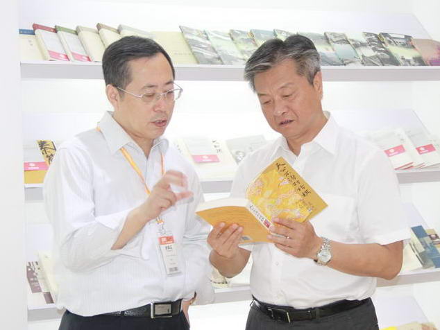 8月26日，一年一度的北京国际图书博览会（BIBF）正式拉开序幕。图为中国出版集团公司总裁谭跃翻阅集团展区图书，三联书店总编辑翟德芳介绍情况。