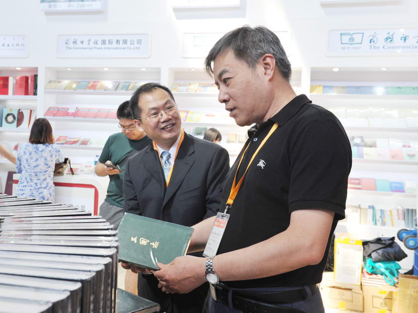 8月26日，一年一度的北京国际图书博览会（BIBF）正式拉开序幕。图为中国出版集团公司副总裁潘凯雄翻阅集团展区图书，商务印书馆副总编辑陈小文介绍情况。