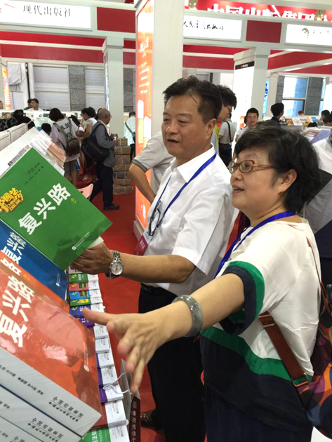 7月28日，主题为“阅草原文化、品华夏书香”的第26届中国图书交易博览会在内蒙古包头市正式启幕。中国出版集团公司总裁谭跃（左一）视察中国民主法制出版社展区。中国民主法制出版社副总编赵卜慧（右一）介绍展区图书。