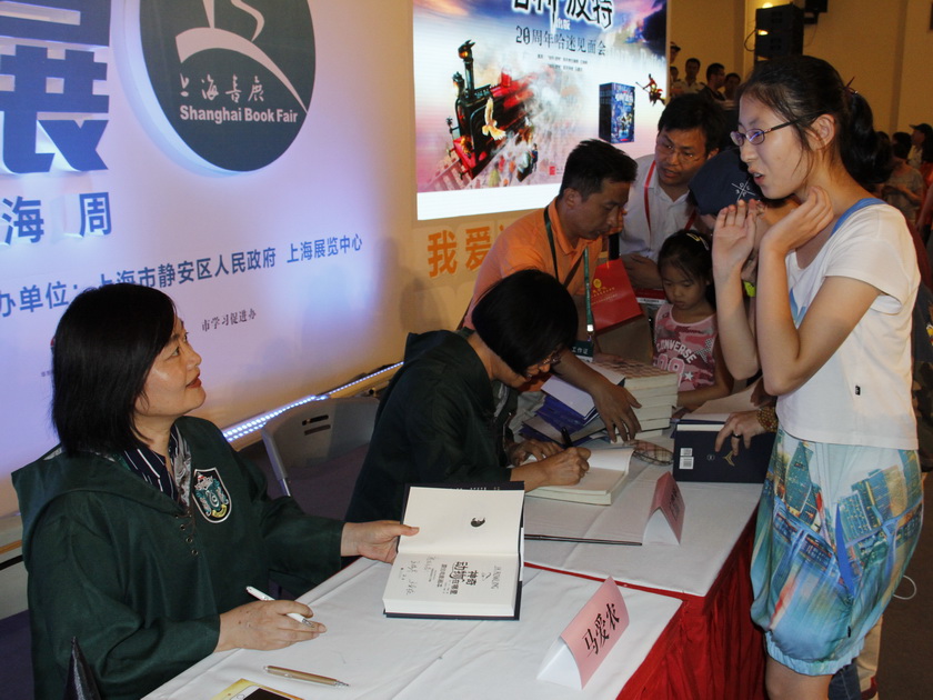 8月18日，人民文学出版社在上海书展举行了“哈利·波特”出版20周年哈迷见面会，该书中文版责任编辑王瑞琴、译者马爱农亲临现场，与读者共同回忆了翻译出版“哈利·波特”系列作品的难忘经历。图为王瑞琴、马爱农为读者签售。